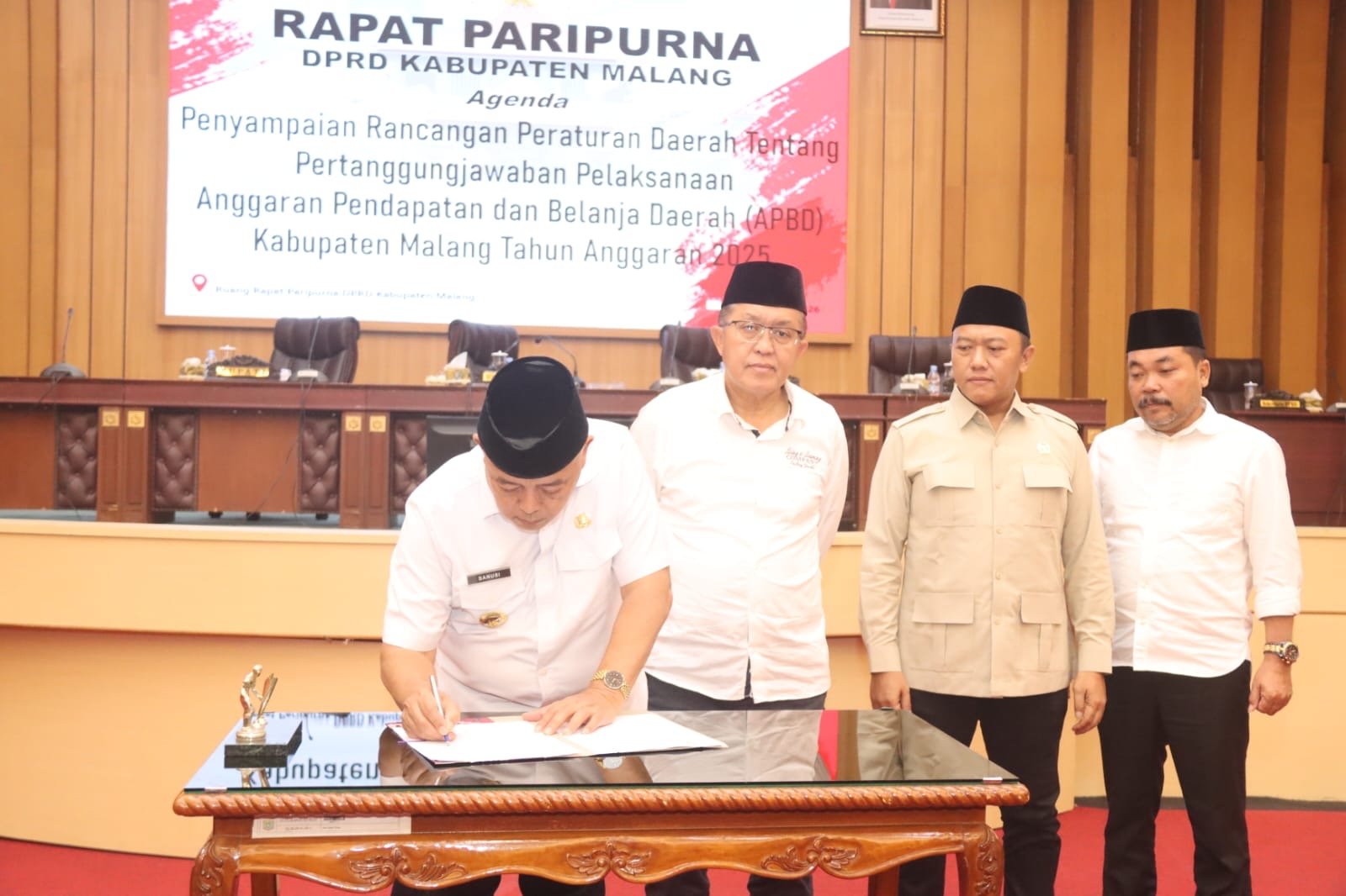 Bupati Malang HM Sanusi saat menandatangani dokumen resmi dalam Rapat Paripurna DPRD Kabupaten Malang yang membahas pertanggungjawaban APBD Tahun 2025.