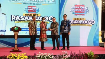 SIDOARJO, JADIKABAR – Cara pedagang membayar retribusi pasar di Kabupaten Sidoarjo mulai memasuki babak baru. Sistem pembayaran yang selama ini identik dengan uang tunai dan karcis manual perlahan bergeser ke layanan digital melalui aplikasi MyRetribusi. Perubahan tersebut diperkuat dengan peluncuran PASAR JAGO (Pasar Sidoarjo Jaringan Go-Digital) dalam High Level Meeting (HLM) Tim Percepatan dan Perluasan Digitalisasi Daerah (TP2DD) Kabupaten Sidoarjo di Pendopo Delta Wibawa, Kamis (13/8/2026). Program ini tidak sekadar diarahkan untuk mengubah cara pedagang membayar retribusi. Pemerintah Kabupaten Sidoarjo juga menempatkan digitalisasi sebagai bagian dari upaya memperbaiki pencatatan penerimaan, meningkatkan transparansi, sekaligus mengoptimalkan Pendapatan Asli Daerah (PAD). Pelaksana Tugas (Plt) Kepala Badan Pelayanan Pajak Daerah (BPPD) Kabupaten Sidoarjo, Yudhi Iriyanto, mengatakan penerapan digitalisasi retribusi pasar mulai diintensifkan sejak Mei 2026. Dari total 19 pasar daerah yang menjadi sasaran, sebanyak 12 pasar saat ini telah menerapkan layanan pembayaran digital melalui MyRetribusi. Perkembangan penggunaannya juga menunjukkan peningkatan. Sejak awal implementasi pada Mei 2026, tercatat 2.109 transaksi. Hingga pertengahan Agustus, jumlah tersebut meningkat menjadi 26.093 transaksi berdasarkan dashboard MyRetribusi. “Sejak awal implementasi pada Mei lalu, tercatat 2.109 transaksi. Hingga pertengahan Agustus 2026, jumlahnya sudah mencapai 26.093 transaksi melalui dashboard MyRetribusi,” ujar Yudhi. Menurut Yudhi, peningkatan tersebut menunjukkan bahwa masyarakat, khususnya pedagang pasar, mulai beradaptasi dengan sistem pembayaran digital. Selain perubahan pola transaksi, Pemkab Sidoarjo mencatat adanya peningkatan rata-rata penerimaan retribusi pasar pada periode setelah digitalisasi mulai diterapkan secara intensif. Data BPPD Sidoarjo menunjukkan, rata-rata mutasi rekening pasar pada Januari hingga April 2026 berada di kisaran Rp1,15 miliar per bulan. Sementara pada periode Mei hingga Juli 2026, rata-rata penerimaan tercatat sekitar Rp1,42 miliar per bulan atau meningkat 23,7 persen. Pemkab Sidoarjo mengaitkan perkembangan tersebut dengan penerapan sistem pembayaran digital yang membuat transaksi lebih tercatat dan mudah dipantau. Namun, angka tersebut merupakan data penerimaan pemerintah daerah pada masing-masing periode dan tidak serta-merta berarti seluruh kenaikan disebabkan oleh digitalisasi. Yudhi menilai, keberadaan sistem digital membuat setiap transaksi pembayaran retribusi memiliki pencatatan yang lebih terstruktur. “Digitalisasi memberikan sistem pembayaran yang lebih tercatat, transparan, dan mudah dipantau. Ini penting agar setiap transaksi pembayaran retribusi oleh pedagang dapat masuk dalam sistem dan pada akhirnya memberikan kontribusi optimal bagi PAD,” katanya. Tren pembayaran digital juga terus berkembang. Porsi penerimaan melalui transaksi digital yang pada Mei 2026 baru berada di angka 2,7 persen, kini meningkat menjadi 33,4 persen. Perubahan sistem tersebut juga menyentuh kebiasaan yang selama bertahun-tahun melekat dalam aktivitas retribusi pasar, yakni penggunaan karcis manual. Dalam skema lama, pembayaran retribusi dilakukan secara langsung dan pencatatan masih sangat bergantung pada proses administrasi di lapangan. Digitalisasi kemudian menghadirkan sistem pencatatan elektronik yang memungkinkan transaksi masuk ke dalam sistem dan lebih mudah dipantau. Pemkab Sidoarjo menargetkan penerapan digitalisasi secara penuh mulai 2027. Jika target tersebut terealisasi, pemerintah daerah memproyeksikan tidak lagi membutuhkan biaya pencetakan karcis retribusi secara manual. Anggaran untuk pencetakan karcis selama ini diperkirakan mencapai sekitar Rp500 juta per tahun. Dengan demikian, digitalisasi tidak hanya dipandang dari sisi kemudahan pembayaran, tetapi juga berpotensi mengurangi kebutuhan biaya administrasi pemerintah daerah. Transformasi digital di lingkungan pasar Sidoarjo bukan proses yang berlangsung dalam waktu singkat. Sekretaris Daerah Kabupaten Sidoarjo, Fenny Apridawati, mengatakan upaya menuju digitalisasi telah dirintis sejak 2017. Artinya, pengembangan sistem tersebut telah melewati proses panjang untuk membangun kesiapan pengelola pasar, pedagang, serta masyarakat. “Kalau kita melihat perjalanan sejak 2017 sampai sekarang, tentu itu bukan waktu yang singkat. Hampir sembilan tahun kita membangun pemahaman dan kesiapan bersama. Hari ini kita ingin menunjukkan bahwa komitmen digitalisasi itu sudah semakin nyata,” ujar Fenny. Menurut Fenny, peluncuran PASAR JAGO menjadi salah satu penanda bahwa proses digitalisasi pasar di Sidoarjo mulai masuk pada tahap yang lebih konkret. Pemerintah daerah tidak hanya dituntut menyediakan teknologi, tetapi juga memastikan teknologi tersebut dapat digunakan masyarakat dengan mudah. “Digitalisasi ini bukan hanya soal bagaimana membayar retribusi. Lebih jauh, ini tentang bagaimana pemerintah memberikan pelayanan yang mengikuti kebutuhan masyarakat,” jelasnya. Bagi Pemkab Sidoarjo, substansi PASAR JAGO tidak berhenti pada perubahan metode pembayaran. Ada persoalan tata kelola yang ingin dibangun melalui sistem tersebut. Setiap transaksi diharapkan dapat tercatat lebih baik sehingga pemerintah mempunyai data penerimaan yang lebih terukur dan mudah dipantau. Pedagang juga tidak lagi sepenuhnya bergantung pada transaksi tunai ketika melakukan pembayaran retribusi. Fenny mengatakan transformasi digital tersebut ke depan diharapkan dapat diperluas ke berbagai lini pelayanan pemerintahan. “Ke depan, digitalisasi harus masuk ke semua lini. Kita ingin masyarakat semakin terbiasa menggunakan pembayaran digital. Sehingga, pelayanan pemerintah menjadi lebih praktis, transparan, dan akuntabel,” tegasnya. Target tersebut sekaligus menjadi tantangan. Sebab, keberhasilan digitalisasi tidak hanya ditentukan oleh keberadaan aplikasi, tetapi juga oleh kesiapan pengguna dan petugas yang menjalankan sistem di lapangan. Yudhi menilai para juru pungut retribusi pasar mempunyai posisi penting dalam keberhasilan program tersebut. Mereka merupakan petugas yang berhadapan langsung dengan pedagang dan masyarakat sehingga menjadi bagian penting dalam proses perubahan dari sistem manual menuju digital. Karena itu, pemerintah memberikan perhatian terhadap proses adaptasi para juru pungut. “Yang paling penting adalah bagaimana sistem tersebut benar-benar digunakan dan memudahkan masyarakat. Karena itu, kami memberikan apresiasi kepada para juru pungut yang mau beradaptasi dan menjadi bagian penting dari perubahan ini,” kata Yudhi. Pemkab Sidoarjo berharap digitalisasi dapat diperluas dari 12 pasar yang saat ini telah menerapkan MyRetribusi hingga mencakup seluruh 19 pasar daerah. Pengembangan PASAR JAGO juga mendapat dukungan Bank Indonesia (BI) dan Bank Jatim melalui penguatan ekosistem pembayaran digital. Dukungan tersebut antara lain melalui penyediaan QRIS Experience dan infrastruktur pembayaran untuk mendukung transaksi retribusi pasar. Bank Indonesia menilai penguatan sistem pembayaran digital merupakan bagian dari upaya menjaga stabilitas sistem pembayaran sekaligus mendukung aktivitas ekonomi yang berkelanjutan. Ekosistem pembayaran yang aman, efisien, dan mudah diakses dinilai penting untuk menunjang aktivitas masyarakat. Dengan peluncuran PASAR JAGO, Pemkab Sidoarjo kini memiliki target yang lebih besar: membawa seluruh pasar daerah masuk ke ekosistem pembayaran digital. Jika implementasi berjalan sesuai rencana, perubahan tersebut bukan hanya akan mengubah cara pedagang membayar retribusi, tetapi juga dapat menjadi bagian dari pembenahan tata kelola penerimaan daerah. Bagi pedagang, tantangannya adalah beradaptasi dengan kebiasaan baru. Bagi pemerintah, tantangannya lebih besar: memastikan sistem benar-benar berjalan, mudah digunakan, transparan, serta mampu memberikan pelayanan yang lebih baik. PASAR JAGO pada akhirnya bukan hanya soal pembayaran tanpa uang tunai. Program ini menjadi bagian dari perjalanan panjang Sidoarjo menuju tata kelola pelayanan publik yang semakin terdigitalisasi.