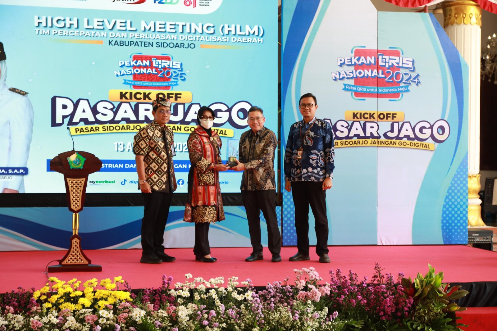 SIDOARJO, JADIKABAR – Cara pedagang membayar retribusi pasar di Kabupaten Sidoarjo mulai memasuki babak baru. Sistem pembayaran yang selama ini identik dengan uang tunai dan karcis manual perlahan bergeser ke layanan digital melalui aplikasi MyRetribusi. Perubahan tersebut diperkuat dengan peluncuran PASAR JAGO (Pasar Sidoarjo Jaringan Go-Digital) dalam High Level Meeting (HLM) Tim Percepatan dan Perluasan Digitalisasi Daerah (TP2DD) Kabupaten Sidoarjo di Pendopo Delta Wibawa, Kamis (13/8/2026). Program ini tidak sekadar diarahkan untuk mengubah cara pedagang membayar retribusi. Pemerintah Kabupaten Sidoarjo juga menempatkan digitalisasi sebagai bagian dari upaya memperbaiki pencatatan penerimaan, meningkatkan transparansi, sekaligus mengoptimalkan Pendapatan Asli Daerah (PAD). Pelaksana Tugas (Plt) Kepala Badan Pelayanan Pajak Daerah (BPPD) Kabupaten Sidoarjo, Yudhi Iriyanto, mengatakan penerapan digitalisasi retribusi pasar mulai diintensifkan sejak Mei 2026. Dari total 19 pasar daerah yang menjadi sasaran, sebanyak 12 pasar saat ini telah menerapkan layanan pembayaran digital melalui MyRetribusi. Perkembangan penggunaannya juga menunjukkan peningkatan. Sejak awal implementasi pada Mei 2026, tercatat 2.109 transaksi. Hingga pertengahan Agustus, jumlah tersebut meningkat menjadi 26.093 transaksi berdasarkan dashboard MyRetribusi. “Sejak awal implementasi pada Mei lalu, tercatat 2.109 transaksi. Hingga pertengahan Agustus 2026, jumlahnya sudah mencapai 26.093 transaksi melalui dashboard MyRetribusi,” ujar Yudhi. Menurut Yudhi, peningkatan tersebut menunjukkan bahwa masyarakat, khususnya pedagang pasar, mulai beradaptasi dengan sistem pembayaran digital. Selain perubahan pola transaksi, Pemkab Sidoarjo mencatat adanya peningkatan rata-rata penerimaan retribusi pasar pada periode setelah digitalisasi mulai diterapkan secara intensif. Data BPPD Sidoarjo menunjukkan, rata-rata mutasi rekening pasar pada Januari hingga April 2026 berada di kisaran Rp1,15 miliar per bulan. Sementara pada periode Mei hingga Juli 2026, rata-rata penerimaan tercatat sekitar Rp1,42 miliar per bulan atau meningkat 23,7 persen. Pemkab Sidoarjo mengaitkan perkembangan tersebut dengan penerapan sistem pembayaran digital yang membuat transaksi lebih tercatat dan mudah dipantau. Namun, angka tersebut merupakan data penerimaan pemerintah daerah pada masing-masing periode dan tidak serta-merta berarti seluruh kenaikan disebabkan oleh digitalisasi. Yudhi menilai, keberadaan sistem digital membuat setiap transaksi pembayaran retribusi memiliki pencatatan yang lebih terstruktur. “Digitalisasi memberikan sistem pembayaran yang lebih tercatat, transparan, dan mudah dipantau. Ini penting agar setiap transaksi pembayaran retribusi oleh pedagang dapat masuk dalam sistem dan pada akhirnya memberikan kontribusi optimal bagi PAD,” katanya. Tren pembayaran digital juga terus berkembang. Porsi penerimaan melalui transaksi digital yang pada Mei 2026 baru berada di angka 2,7 persen, kini meningkat menjadi 33,4 persen. Perubahan sistem tersebut juga menyentuh kebiasaan yang selama bertahun-tahun melekat dalam aktivitas retribusi pasar, yakni penggunaan karcis manual. Dalam skema lama, pembayaran retribusi dilakukan secara langsung dan pencatatan masih sangat bergantung pada proses administrasi di lapangan. Digitalisasi kemudian menghadirkan sistem pencatatan elektronik yang memungkinkan transaksi masuk ke dalam sistem dan lebih mudah dipantau. Pemkab Sidoarjo menargetkan penerapan digitalisasi secara penuh mulai 2027. Jika target tersebut terealisasi, pemerintah daerah memproyeksikan tidak lagi membutuhkan biaya pencetakan karcis retribusi secara manual. Anggaran untuk pencetakan karcis selama ini diperkirakan mencapai sekitar Rp500 juta per tahun. Dengan demikian, digitalisasi tidak hanya dipandang dari sisi kemudahan pembayaran, tetapi juga berpotensi mengurangi kebutuhan biaya administrasi pemerintah daerah. Transformasi digital di lingkungan pasar Sidoarjo bukan proses yang berlangsung dalam waktu singkat. Sekretaris Daerah Kabupaten Sidoarjo, Fenny Apridawati, mengatakan upaya menuju digitalisasi telah dirintis sejak 2017. Artinya, pengembangan sistem tersebut telah melewati proses panjang untuk membangun kesiapan pengelola pasar, pedagang, serta masyarakat. “Kalau kita melihat perjalanan sejak 2017 sampai sekarang, tentu itu bukan waktu yang singkat. Hampir sembilan tahun kita membangun pemahaman dan kesiapan bersama. Hari ini kita ingin menunjukkan bahwa komitmen digitalisasi itu sudah semakin nyata,” ujar Fenny. Menurut Fenny, peluncuran PASAR JAGO menjadi salah satu penanda bahwa proses digitalisasi pasar di Sidoarjo mulai masuk pada tahap yang lebih konkret. Pemerintah daerah tidak hanya dituntut menyediakan teknologi, tetapi juga memastikan teknologi tersebut dapat digunakan masyarakat dengan mudah. “Digitalisasi ini bukan hanya soal bagaimana membayar retribusi. Lebih jauh, ini tentang bagaimana pemerintah memberikan pelayanan yang mengikuti kebutuhan masyarakat,” jelasnya. Bagi Pemkab Sidoarjo, substansi PASAR JAGO tidak berhenti pada perubahan metode pembayaran. Ada persoalan tata kelola yang ingin dibangun melalui sistem tersebut. Setiap transaksi diharapkan dapat tercatat lebih baik sehingga pemerintah mempunyai data penerimaan yang lebih terukur dan mudah dipantau. Pedagang juga tidak lagi sepenuhnya bergantung pada transaksi tunai ketika melakukan pembayaran retribusi. Fenny mengatakan transformasi digital tersebut ke depan diharapkan dapat diperluas ke berbagai lini pelayanan pemerintahan. “Ke depan, digitalisasi harus masuk ke semua lini. Kita ingin masyarakat semakin terbiasa menggunakan pembayaran digital. Sehingga, pelayanan pemerintah menjadi lebih praktis, transparan, dan akuntabel,” tegasnya. Target tersebut sekaligus menjadi tantangan. Sebab, keberhasilan digitalisasi tidak hanya ditentukan oleh keberadaan aplikasi, tetapi juga oleh kesiapan pengguna dan petugas yang menjalankan sistem di lapangan. Yudhi menilai para juru pungut retribusi pasar mempunyai posisi penting dalam keberhasilan program tersebut. Mereka merupakan petugas yang berhadapan langsung dengan pedagang dan masyarakat sehingga menjadi bagian penting dalam proses perubahan dari sistem manual menuju digital. Karena itu, pemerintah memberikan perhatian terhadap proses adaptasi para juru pungut. “Yang paling penting adalah bagaimana sistem tersebut benar-benar digunakan dan memudahkan masyarakat. Karena itu, kami memberikan apresiasi kepada para juru pungut yang mau beradaptasi dan menjadi bagian penting dari perubahan ini,” kata Yudhi. Pemkab Sidoarjo berharap digitalisasi dapat diperluas dari 12 pasar yang saat ini telah menerapkan MyRetribusi hingga mencakup seluruh 19 pasar daerah. Pengembangan PASAR JAGO juga mendapat dukungan Bank Indonesia (BI) dan Bank Jatim melalui penguatan ekosistem pembayaran digital. Dukungan tersebut antara lain melalui penyediaan QRIS Experience dan infrastruktur pembayaran untuk mendukung transaksi retribusi pasar. Bank Indonesia menilai penguatan sistem pembayaran digital merupakan bagian dari upaya menjaga stabilitas sistem pembayaran sekaligus mendukung aktivitas ekonomi yang berkelanjutan. Ekosistem pembayaran yang aman, efisien, dan mudah diakses dinilai penting untuk menunjang aktivitas masyarakat. Dengan peluncuran PASAR JAGO, Pemkab Sidoarjo kini memiliki target yang lebih besar: membawa seluruh pasar daerah masuk ke ekosistem pembayaran digital. Jika implementasi berjalan sesuai rencana, perubahan tersebut bukan hanya akan mengubah cara pedagang membayar retribusi, tetapi juga dapat menjadi bagian dari pembenahan tata kelola penerimaan daerah. Bagi pedagang, tantangannya adalah beradaptasi dengan kebiasaan baru. Bagi pemerintah, tantangannya lebih besar: memastikan sistem benar-benar berjalan, mudah digunakan, transparan, serta mampu memberikan pelayanan yang lebih baik. PASAR JAGO pada akhirnya bukan hanya soal pembayaran tanpa uang tunai. Program ini menjadi bagian dari perjalanan panjang Sidoarjo menuju tata kelola pelayanan publik yang semakin terdigitalisasi.
